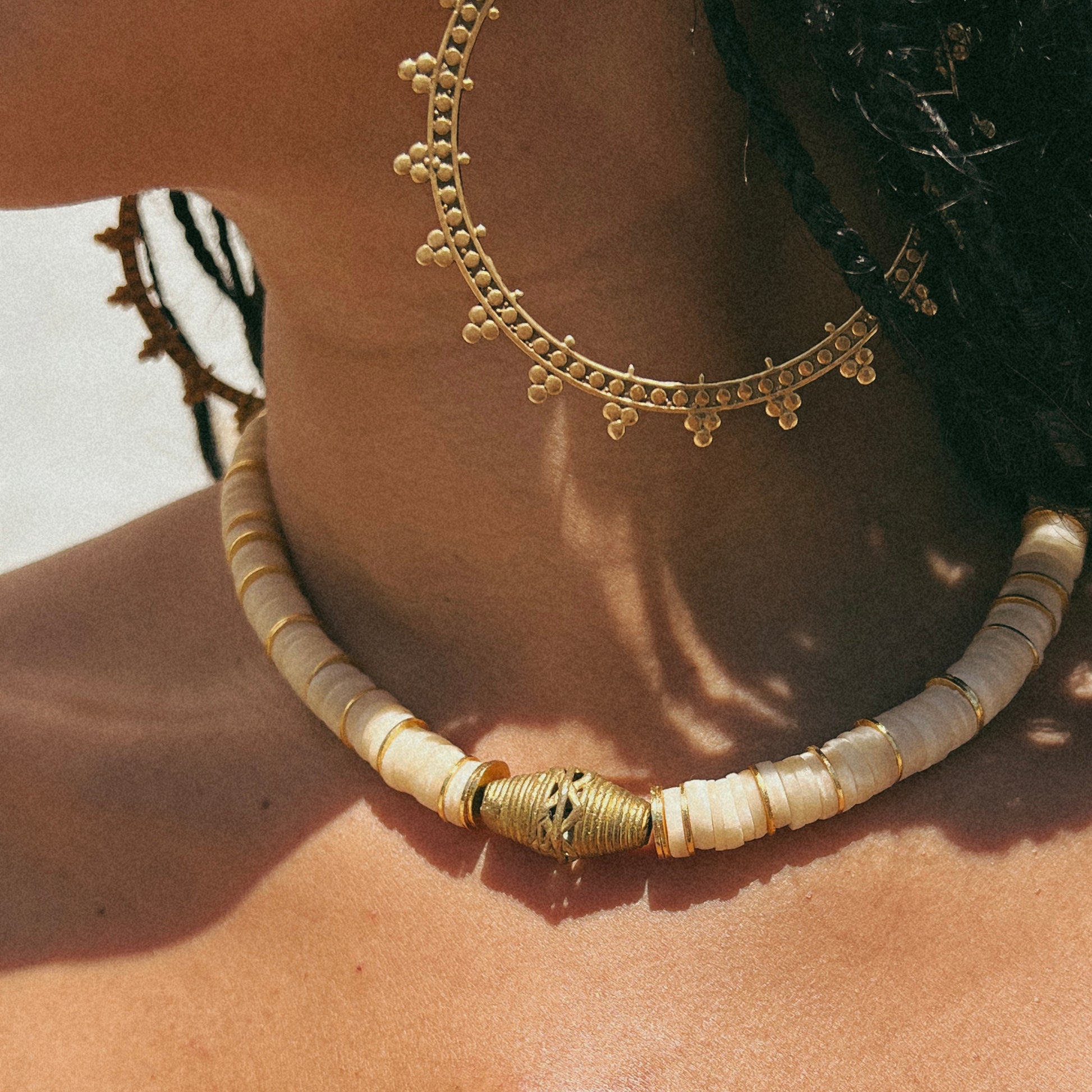 Shell necklace with gold spacers and a brass pendant on model